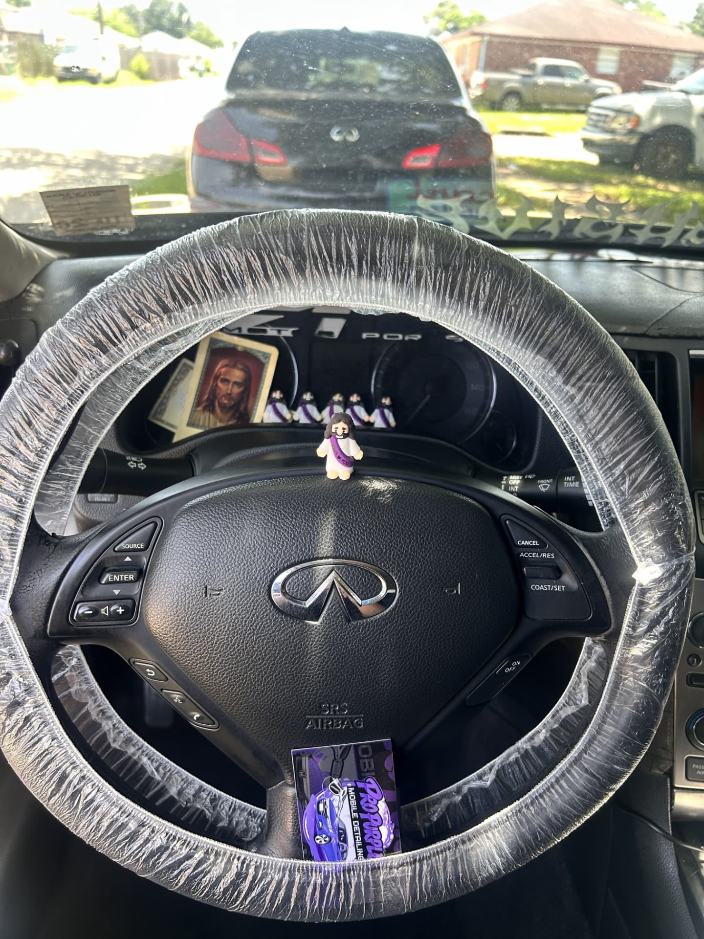 Protective steering wheel cover and Pro Purple business card inside an Infiniti during an interior detail in Kenner, Louisiana