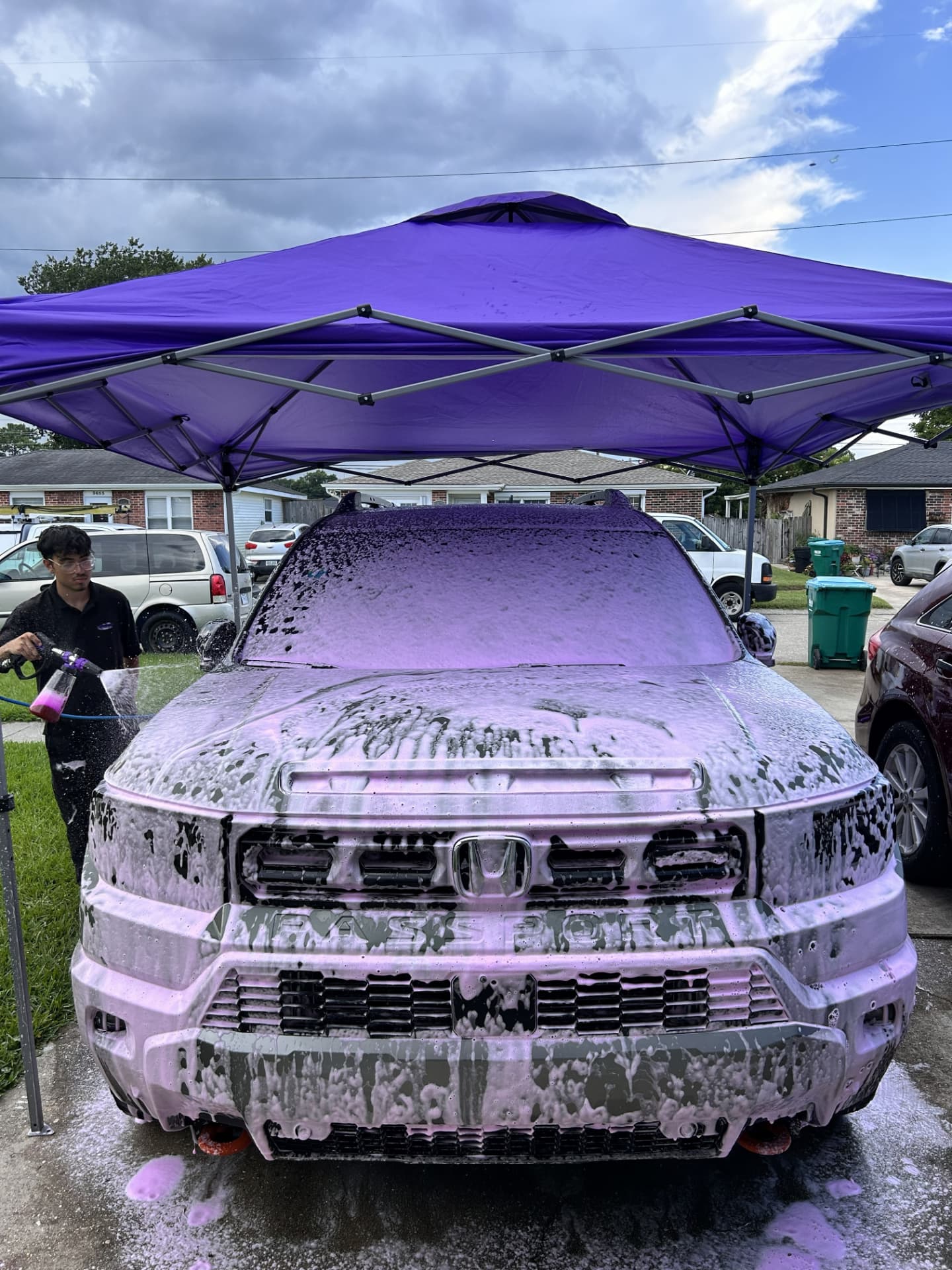 Pro Purple Mobile Detailing technician applying purple snow foam to a Honda Passport under a purple canopy in Kenner, Louisiana