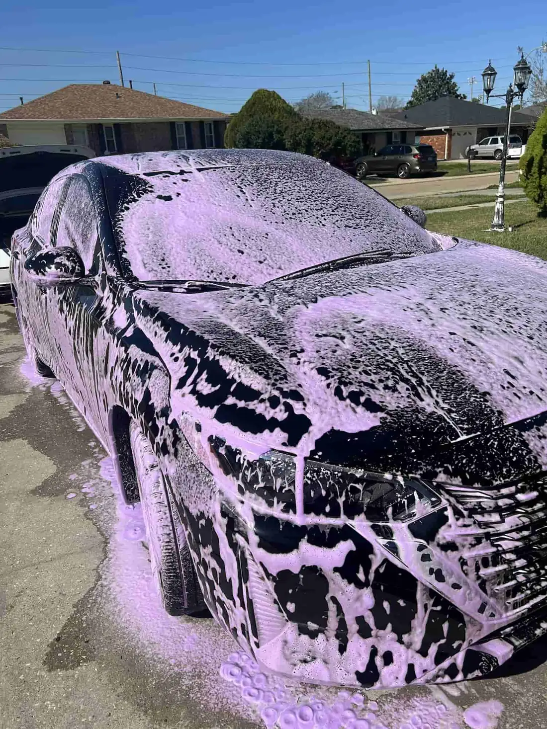 Black Nissan Sentra under thick purple foam during a safe hand wash mobile detail in Kenner, Louisiana